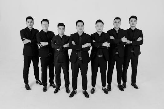 Seven men in elegant suits posing confidently in a studio setting.
