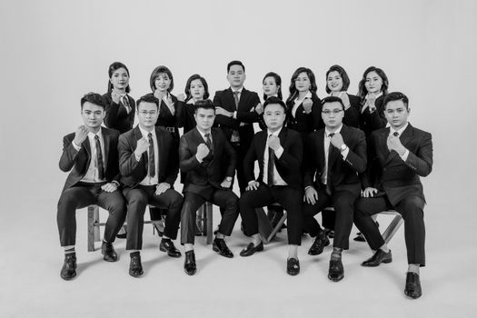 A group of Asian professionals in suits posing confidently in a studio setting.