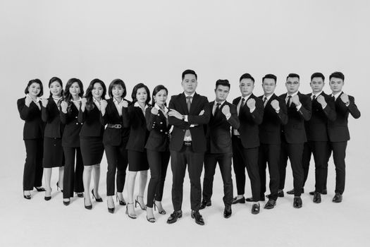 Black and white portrait of a confident, diverse corporate team in formal attire in a studio setting.