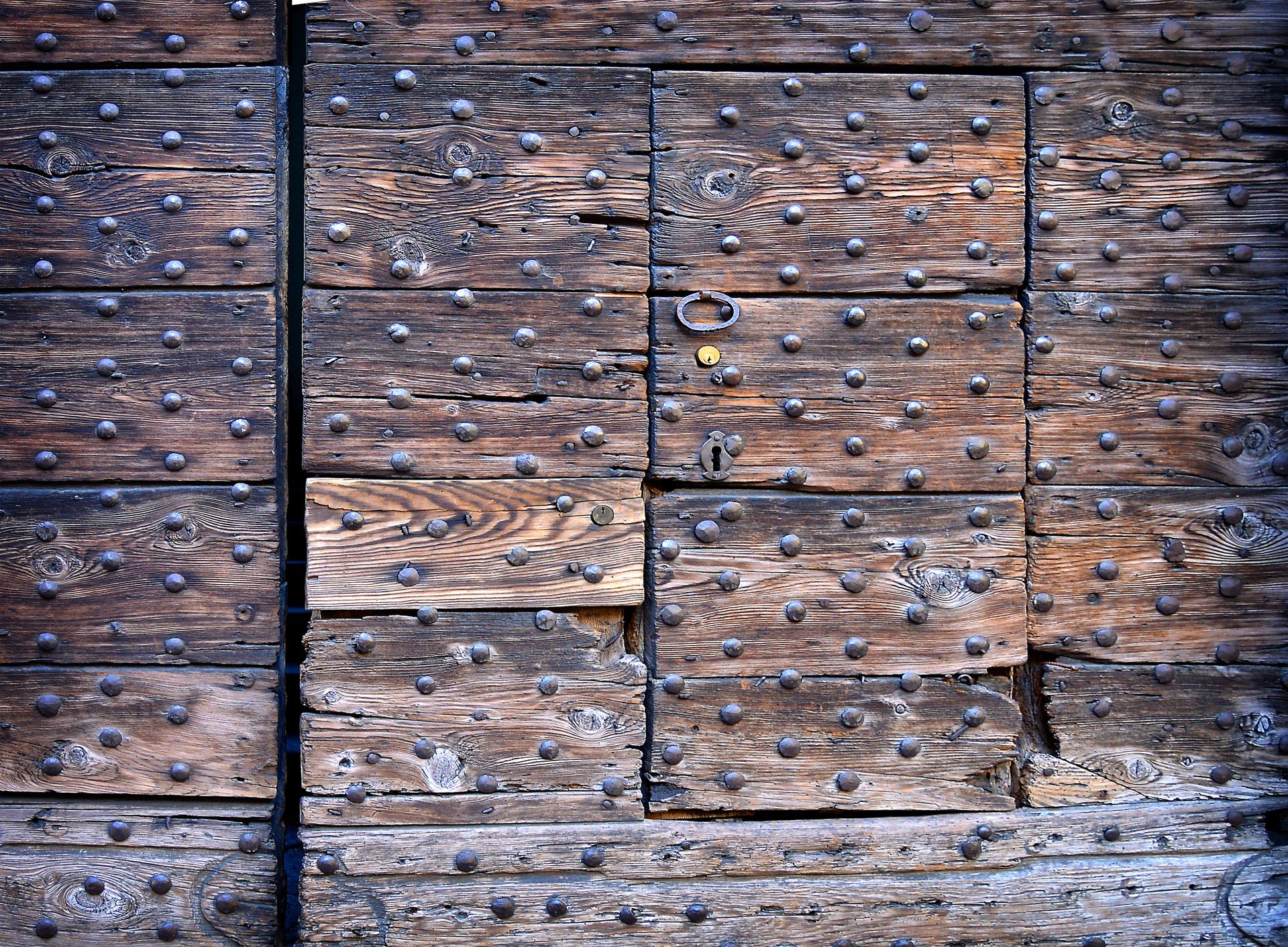 Close-up of a rustic wooden door with metal studs and a weathered texture, perfect for backgrounds.