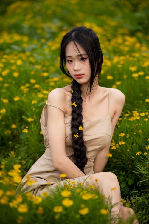 A beautiful young woman sitting in a field of yellow flowers