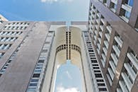 现代摩天大楼的低角度视图与未来风格的拱门在蓝天下形成对比