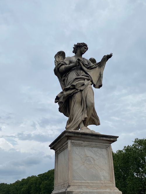 Free Elegant stone statue depicting an angel against a cloudy backdrop. Stock Photo