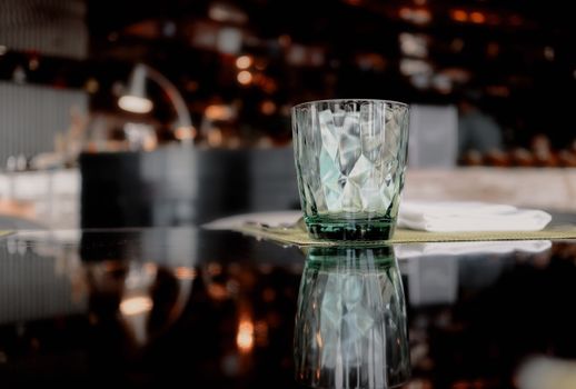 Close-up of a textured glass with reflection on a surface in a warm, ambient indoor space.