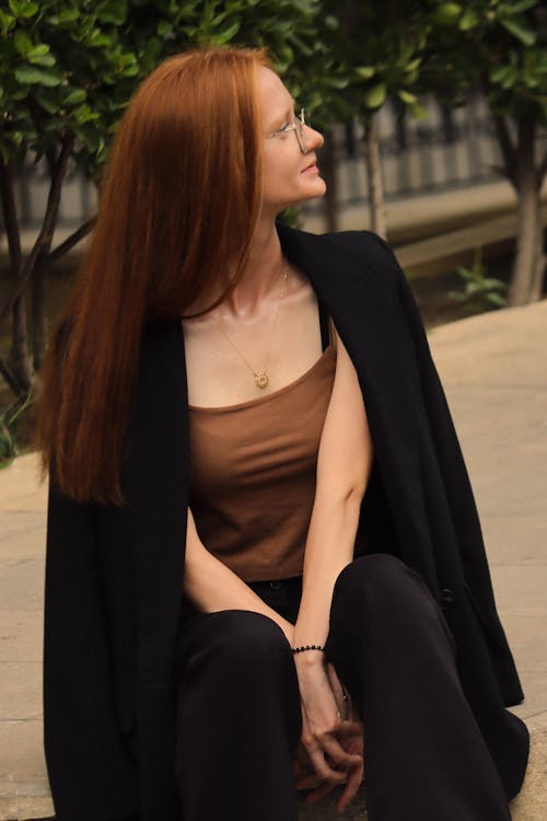 A woman with red hair sitting on a bench