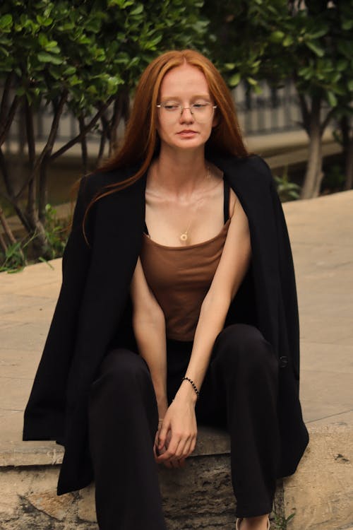 A woman with red hair sitting on a bench