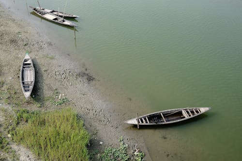 Free Three boats are sitting on the shore of a body of water Stock Photo