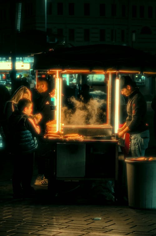 A group of people standing around a food cart