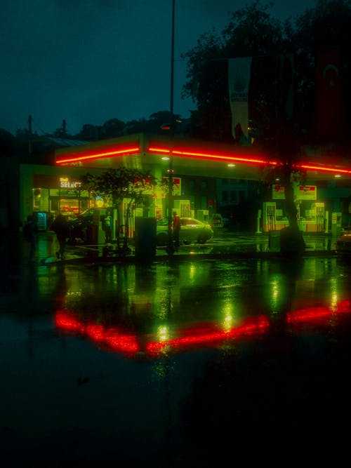 A gas station lit up at night with green lights