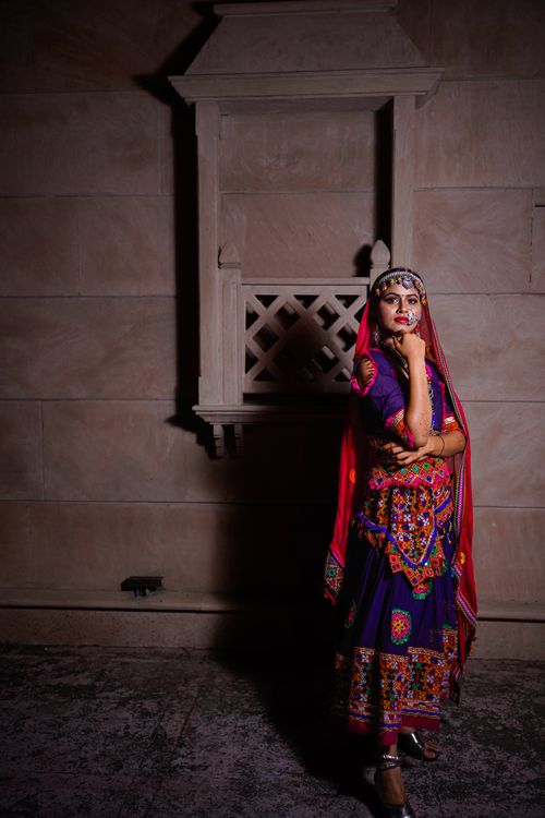 Free Indian woman in traditional colorful attire posing against a stone facade at dusk. Stock Photo