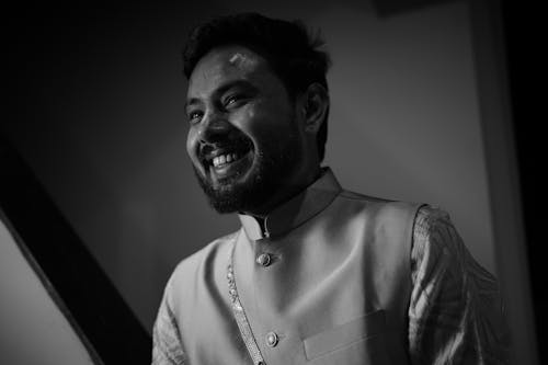 A man in a white shirt and vest smiling