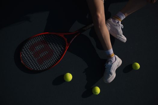 A close-up shot of a tennis player on a court with a racket and tennis balls.
