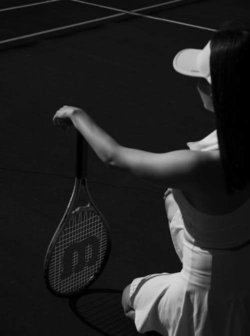 A woman in a white dress holding a tennis racket