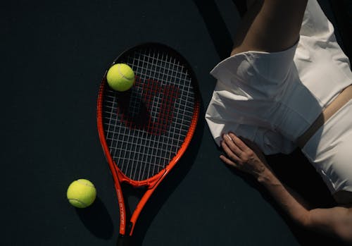 Free A woman laying on the ground with a tennis racket Stock Photo