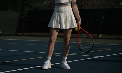 A woman in white tennis outfit holding a tennis racket