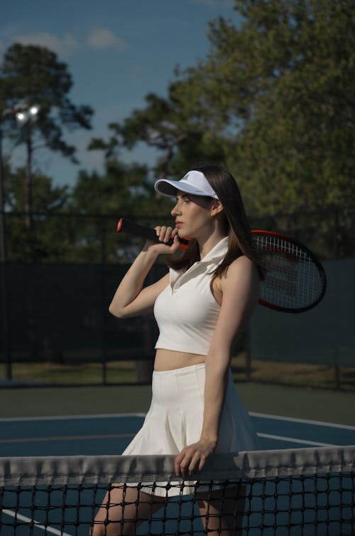 A woman in a white tennis outfit holding a tennis racket