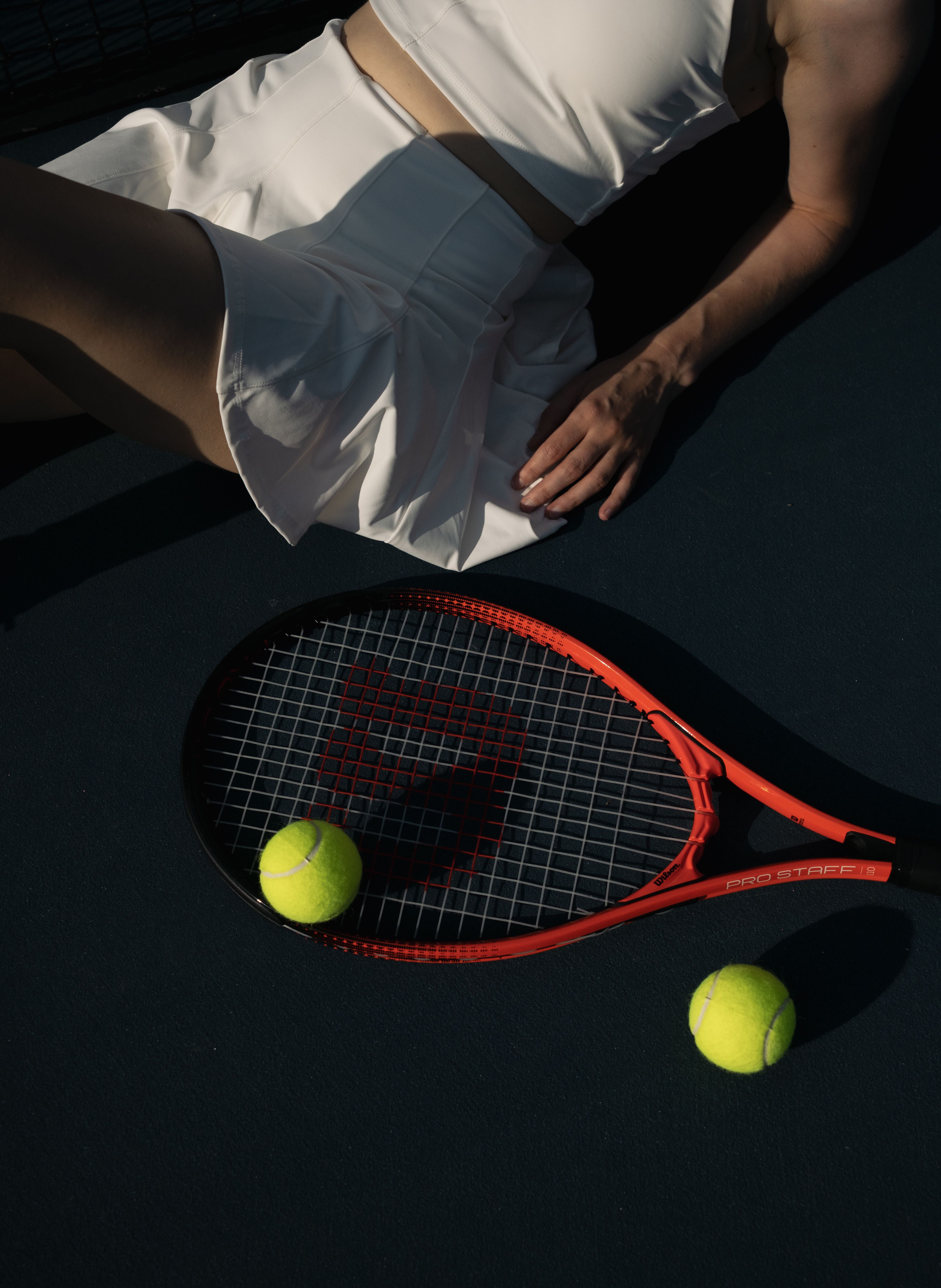 A Racket, Tennis Balls, and a Part of Woman Body · Free Stock Photo