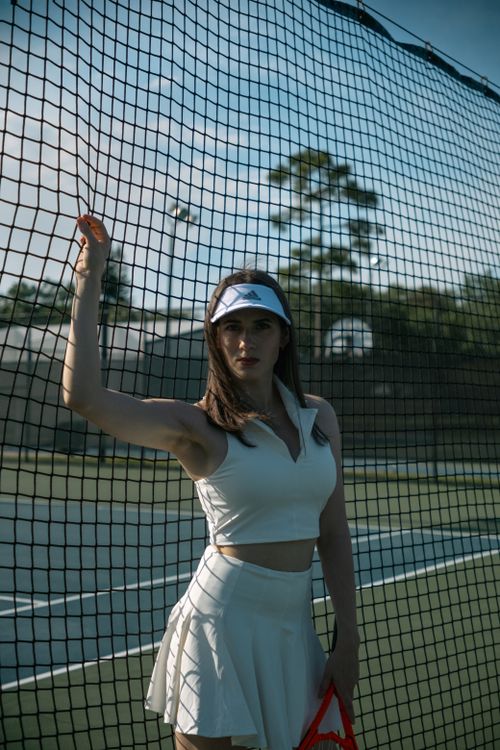 Free Young woman poses confidently at a tennis court in stylish sportswear. Stock Photo