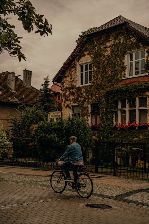 A person riding a bike down a street in front of a house