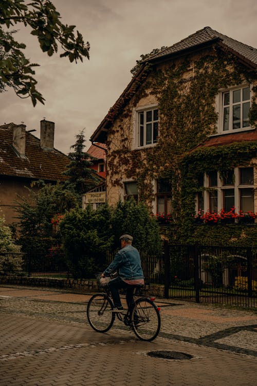 Free A person riding a bike down a street in front of a house Stock Photo