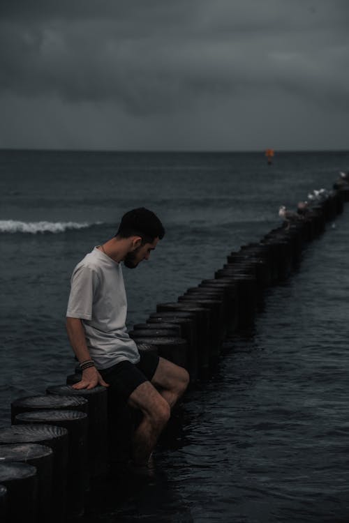 A man sitting on a pier in the ocean