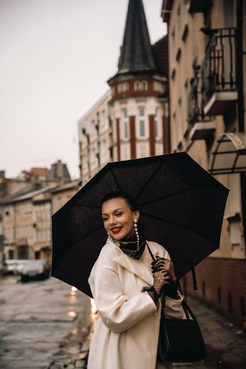 A woman in a white coat and black umbrella