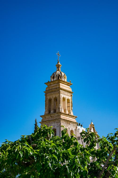 Free Tall historic church tower in Pedro Meoqui, Mexico against a bright blue sky and greenery. Stock Photo