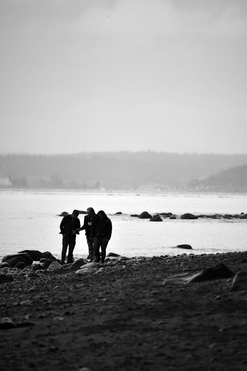 Black and white photograph of three people standing on the beach