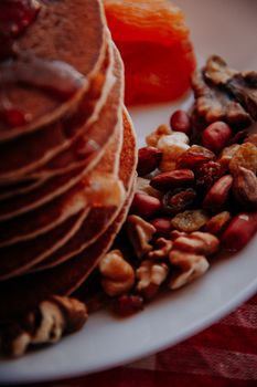 Delicious stack of pancakes with nuts and dried fruit, perfect for breakfast.