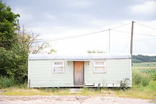Free Photo of a rustic wooden cabin surrounded by countryside and utility poles. Stock Photo