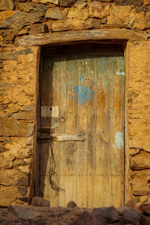 A wooden door in a stone wall with a blue sign