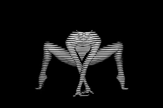 美术裸体照片通过创意性地运用阴影和条纹，营造出优雅的审美氛围