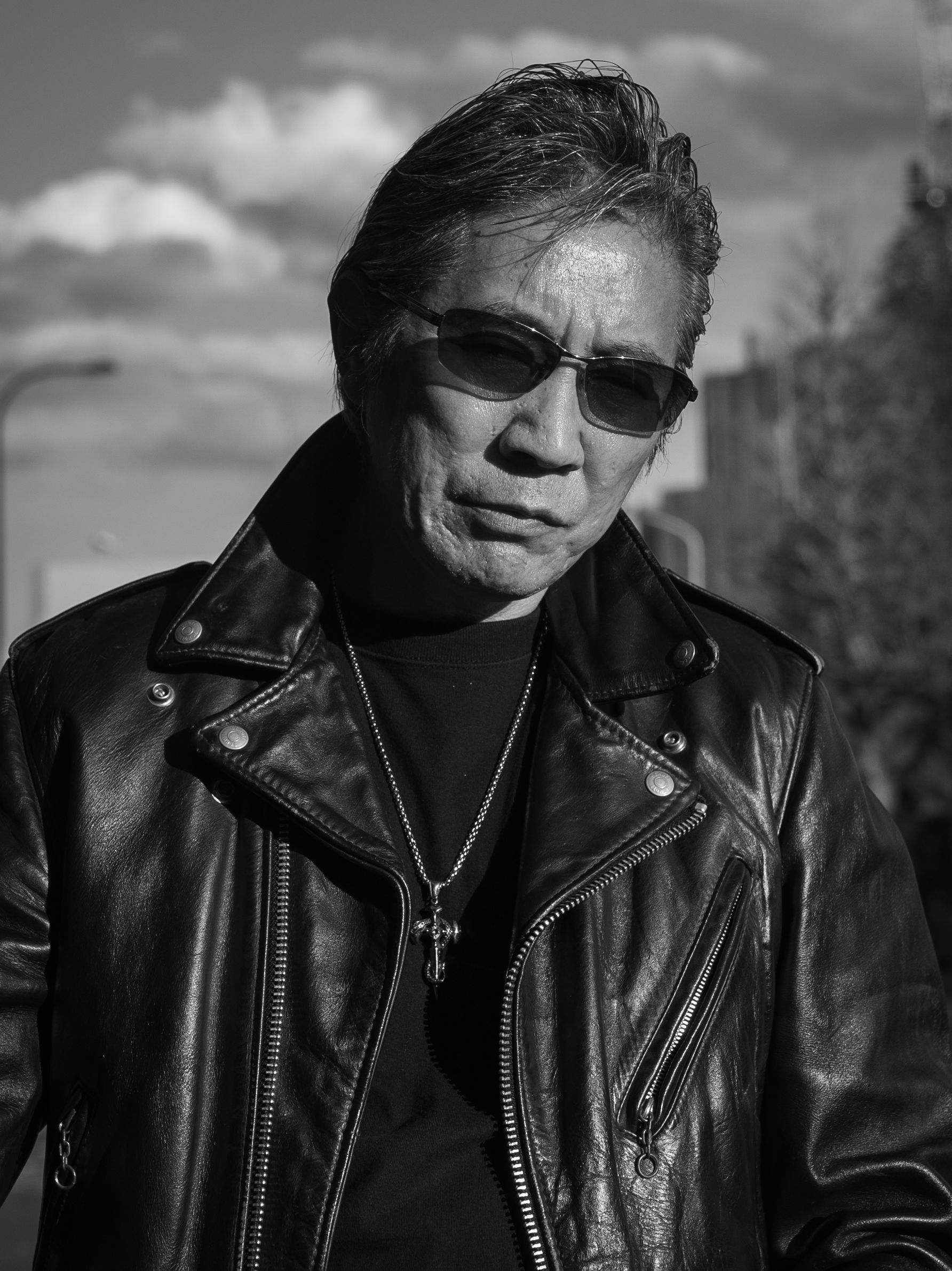 Black and white portrait of a man wearing a leather jacket and sunglasses in Tokyo.