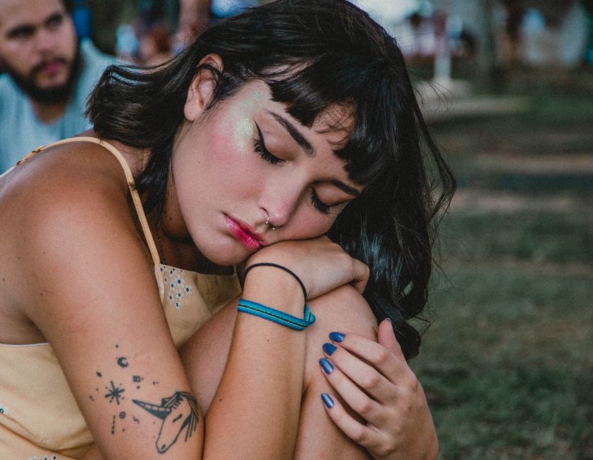 Close-up of a resting woman with tattoos enjoying a tranquil outdoor moment.