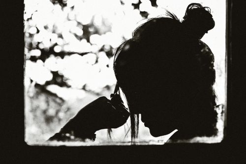 Free Black and white silhouette of a woman in contemplation by a window in Dalat, Vietnam. Stock Photo
