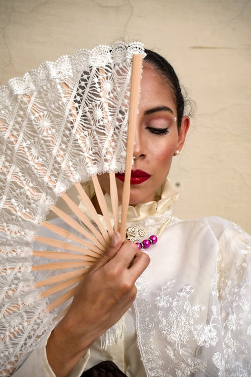 Free A woman in a white lace dress holding a fan Stock Photo