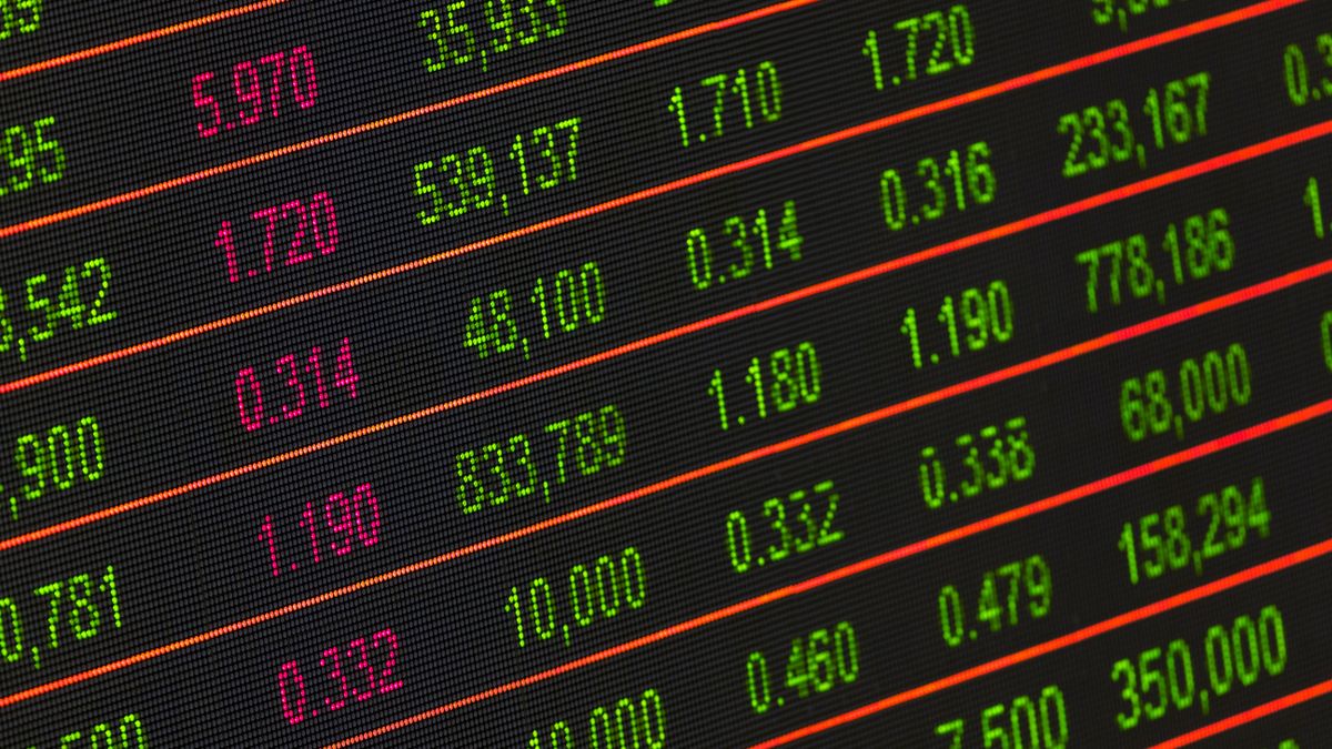 Painel eletrônico de bolsa de valores exibindo cotações e variações de ações em cores