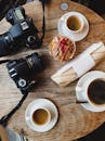 俯视木桌，上面摆着咖啡、零食和单反相机，展现了食物与摄影的完美融合