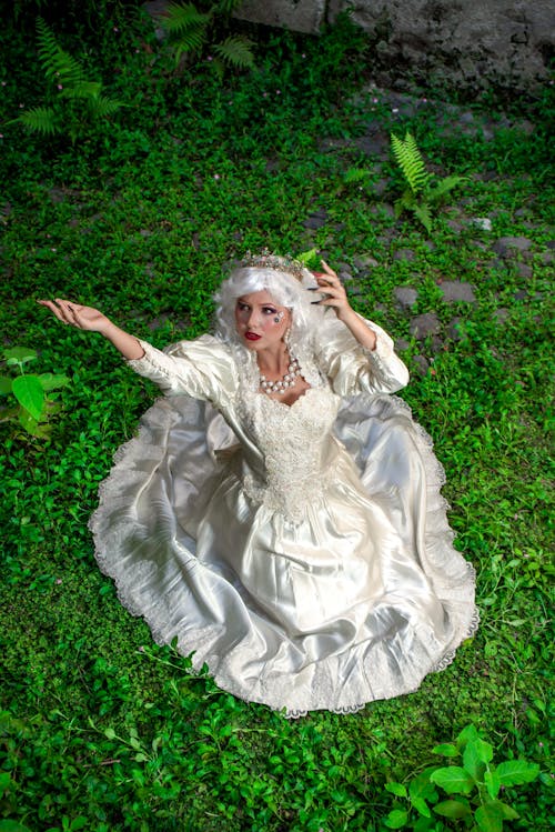 A woman in a white dress sitting on the grass