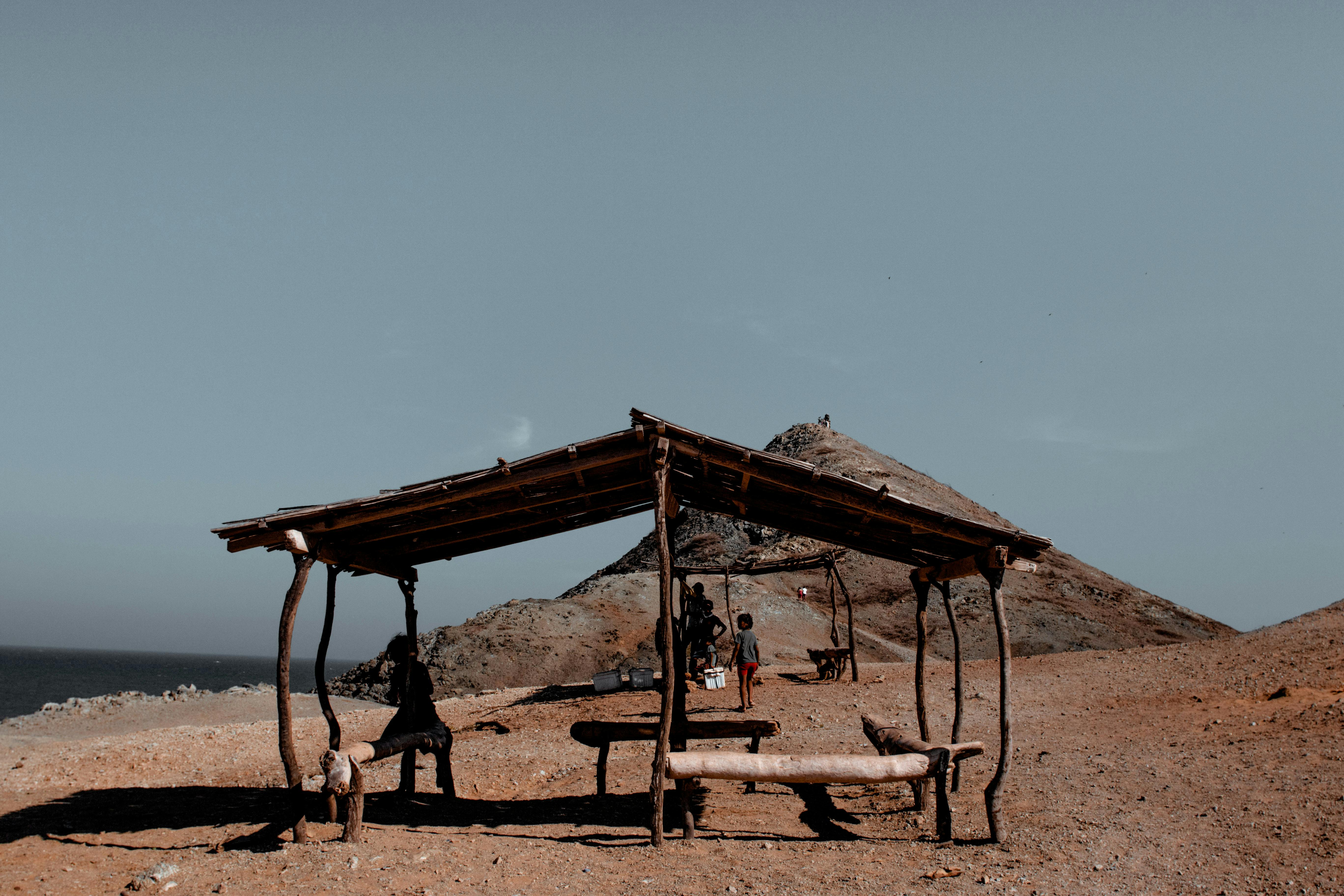 在沙漠景观中，孩子们在僻静的木制避难所下玩耍，映衬出孤独感