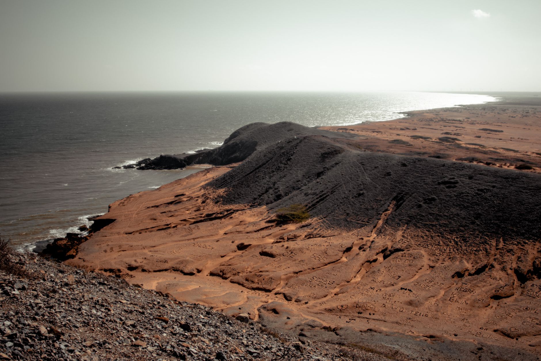 A stunning coastal landscape of a rocky desert beach meeting the ocean under a clear sky.