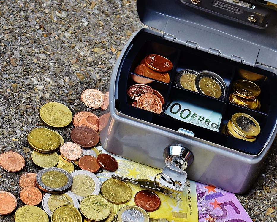 Open Gray Cash Box Beside Scatterd Coins
