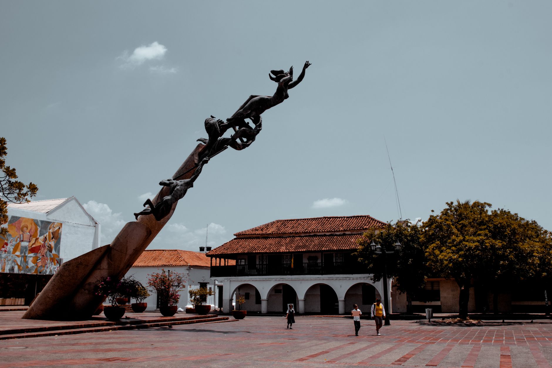A quiet Colombian town plaza with a closed cockfighting arena, police signage, and concerned residents