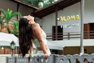 一个快乐的女人穿着白色服装，快乐地靠在户外的栅栏上