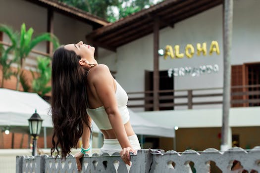 一个快乐的女人穿着白色服装，快乐地靠在户外的栅栏上