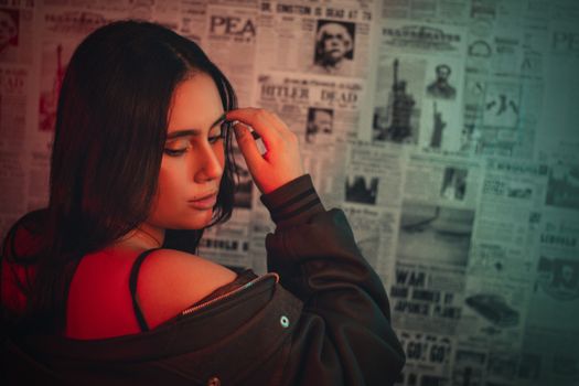 Moody portrait of a young woman with long brunette hair, set against vintage newspapers.