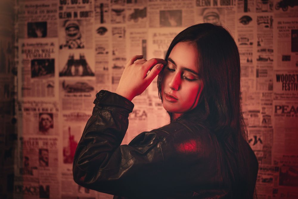 Stylish portrait of a woman in a black leather jacket with a newspaper backdrop