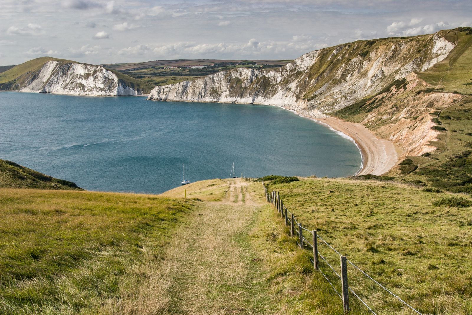 Grass path along coastal cliffs above a bay, by Emil Zimmermann on Pexels