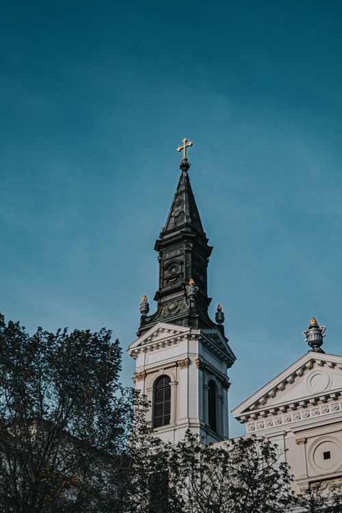 Free A classic church tower featuring a prominent cross under a clear blue sky, symbolizing religion and architecture. Stock Photo