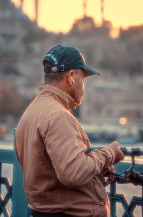 A man in a hat and jacket is looking at his phone